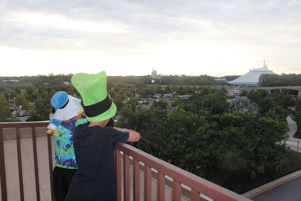 two kids looking out a window at trees and buildings