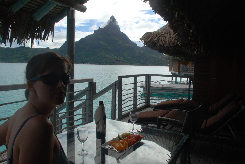 a woman sitting at a table with a plate of fruit on it