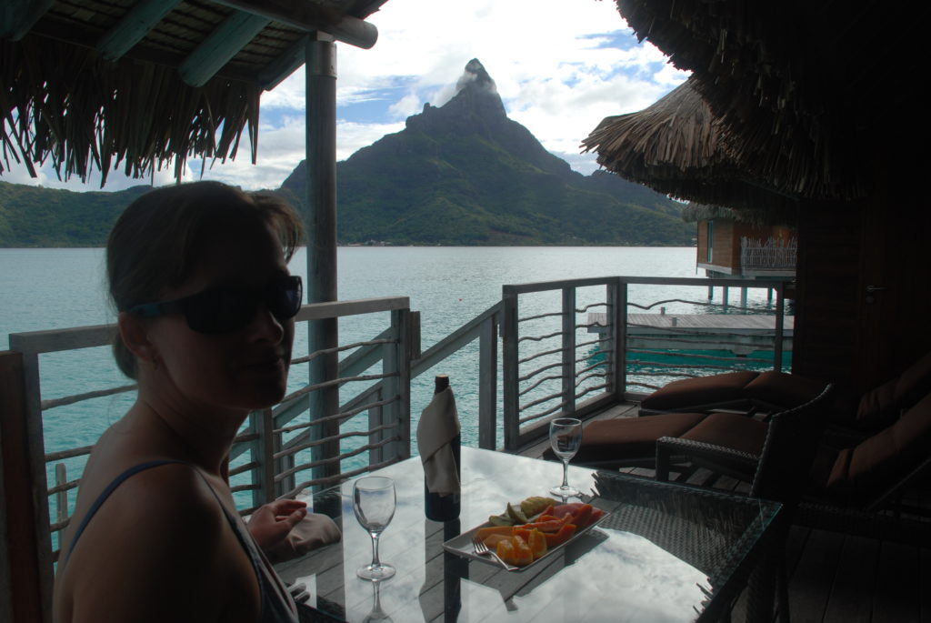a woman sitting at a table with a mountain in the background