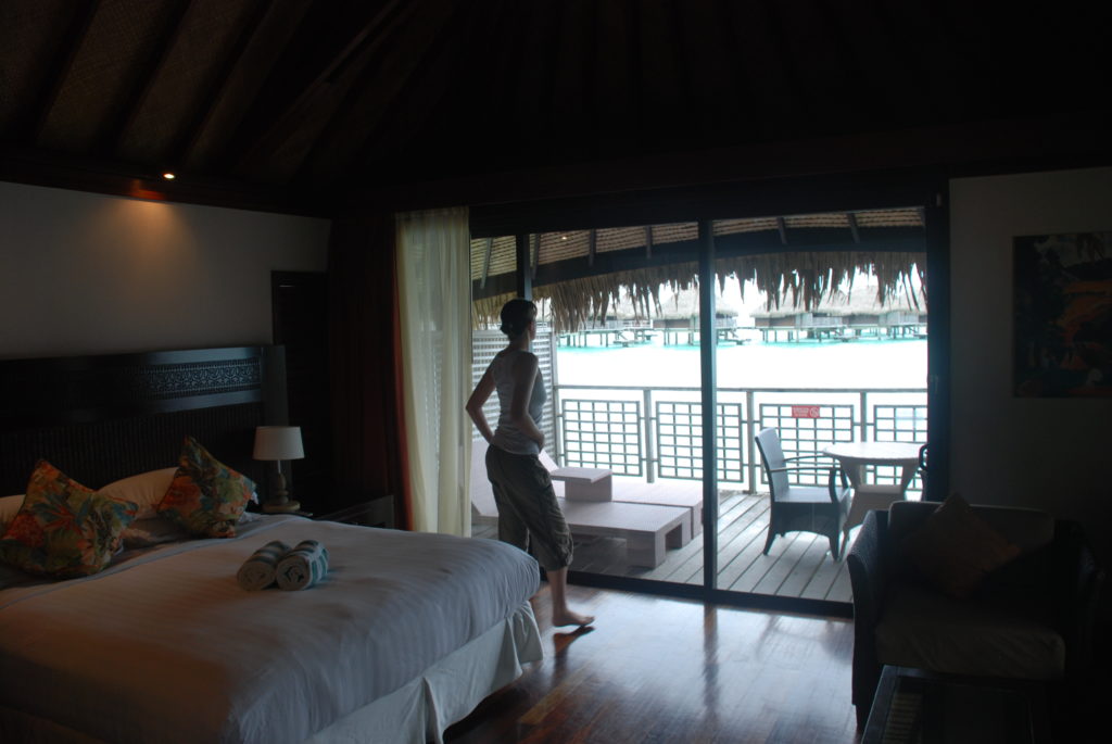 a woman standing in a room with a bed and a window