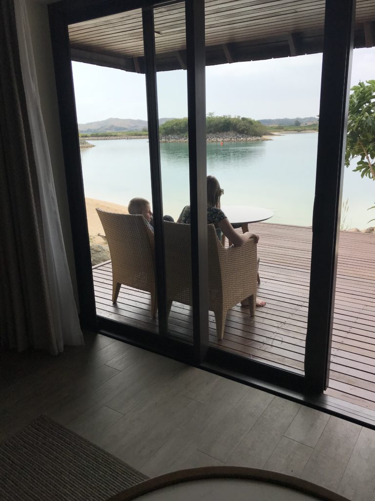 a woman and child sitting on a deck overlooking a body of water