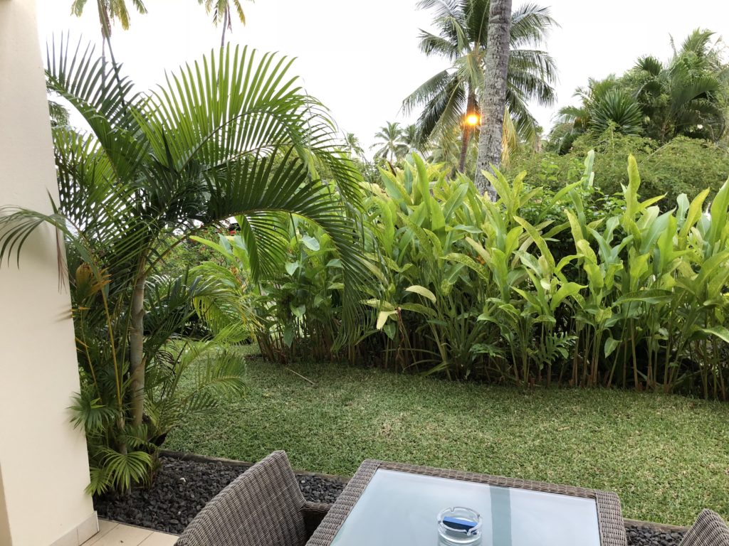 a patio with a table and chairs and palm trees