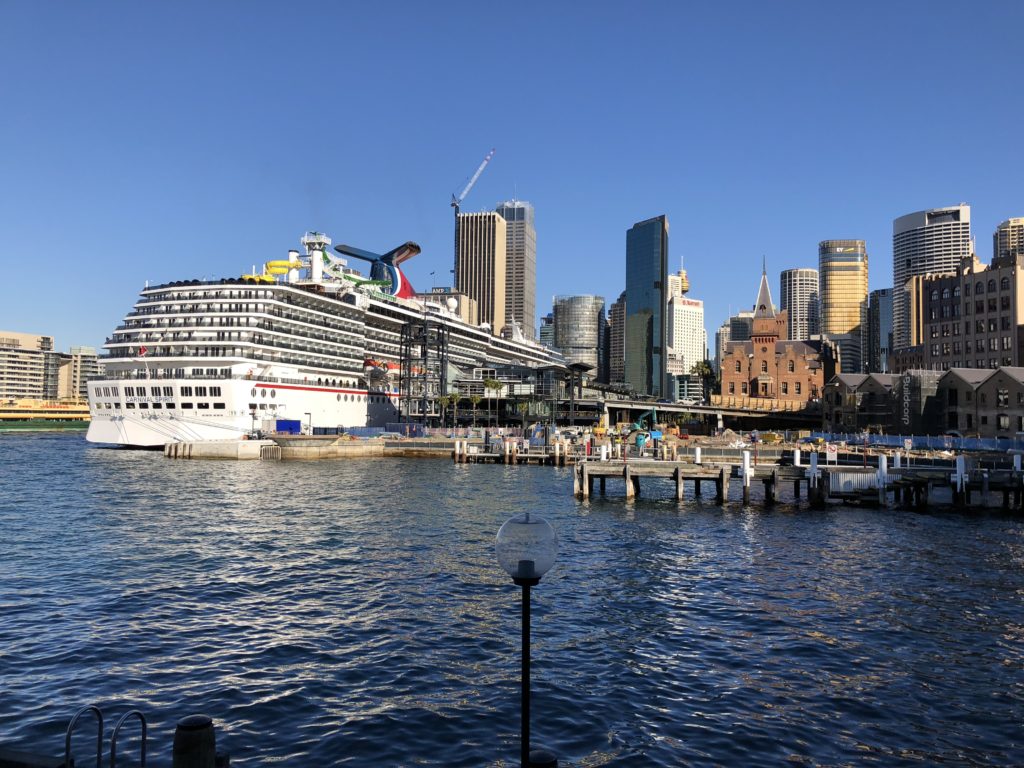 a cruise ship docked in a harbor with a city in the background