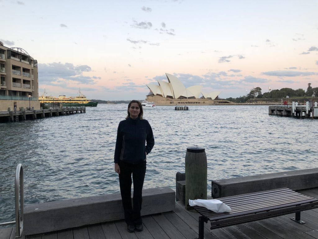 a woman standing on a dock by water with a building in the background