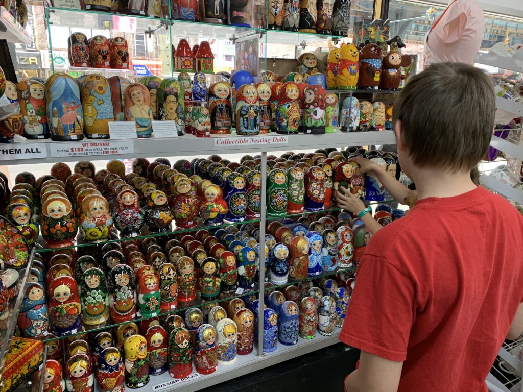 a boy touching a display of russian dolls
