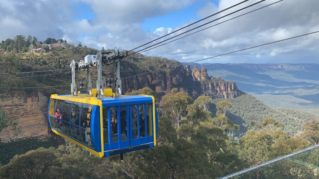a gondola with a blue and yellow cab over a mountain