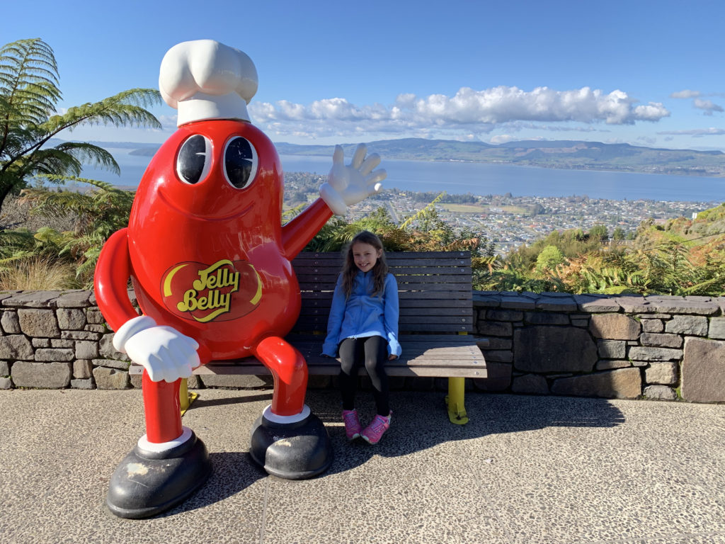 a girl sitting on a bench with a large red and white character