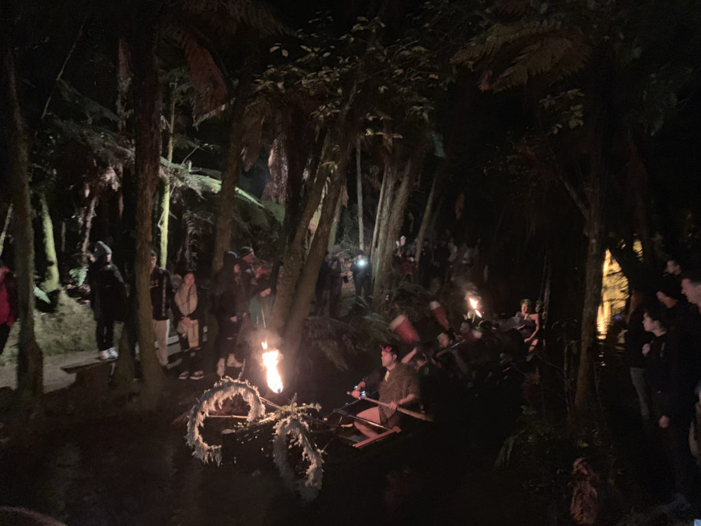 a group of people in a boat with a fire in the woods