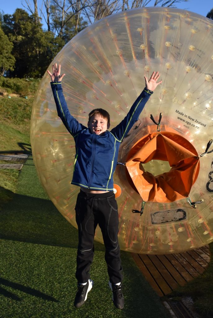 a boy standing in front of a large plastic ball