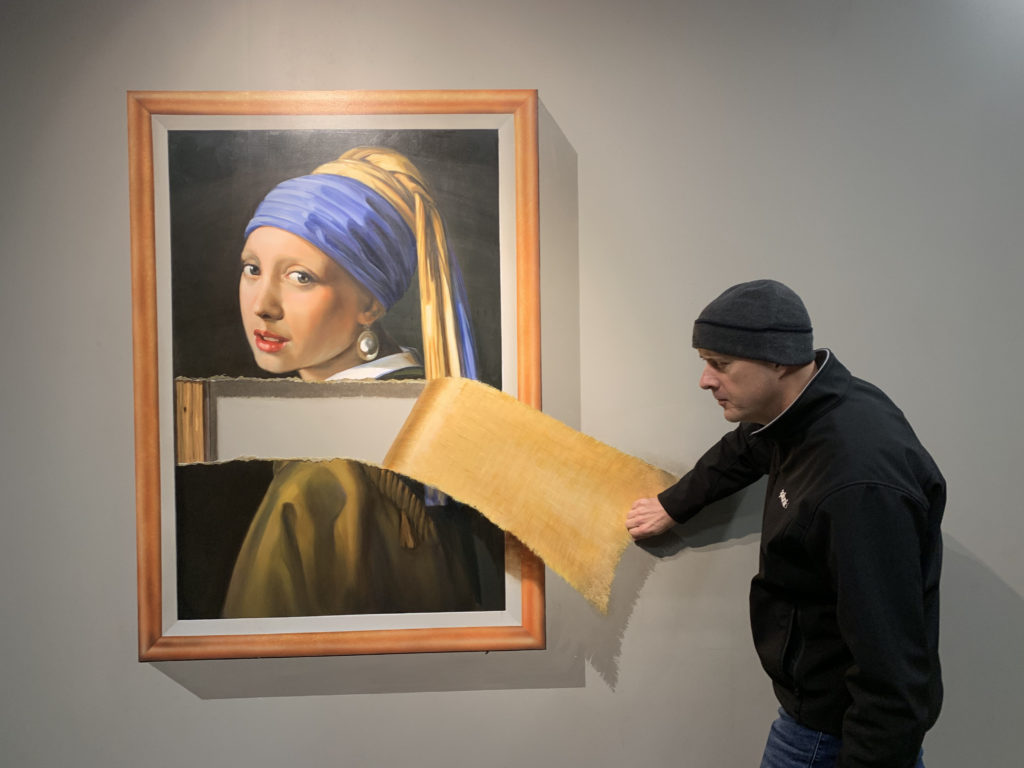 a man putting a piece of paper on a painting