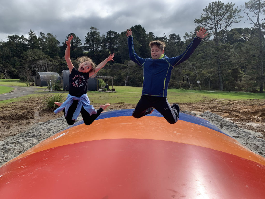 a boy and girl jumping on a large inflatable ball