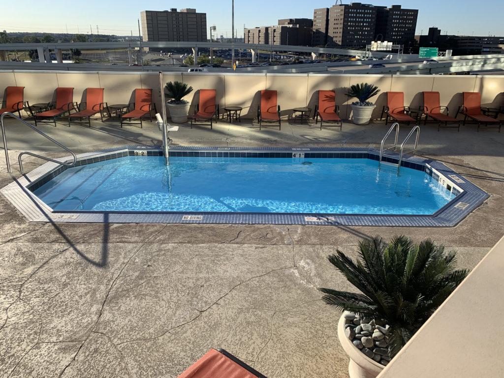 a pool with chairs and a building in the background
