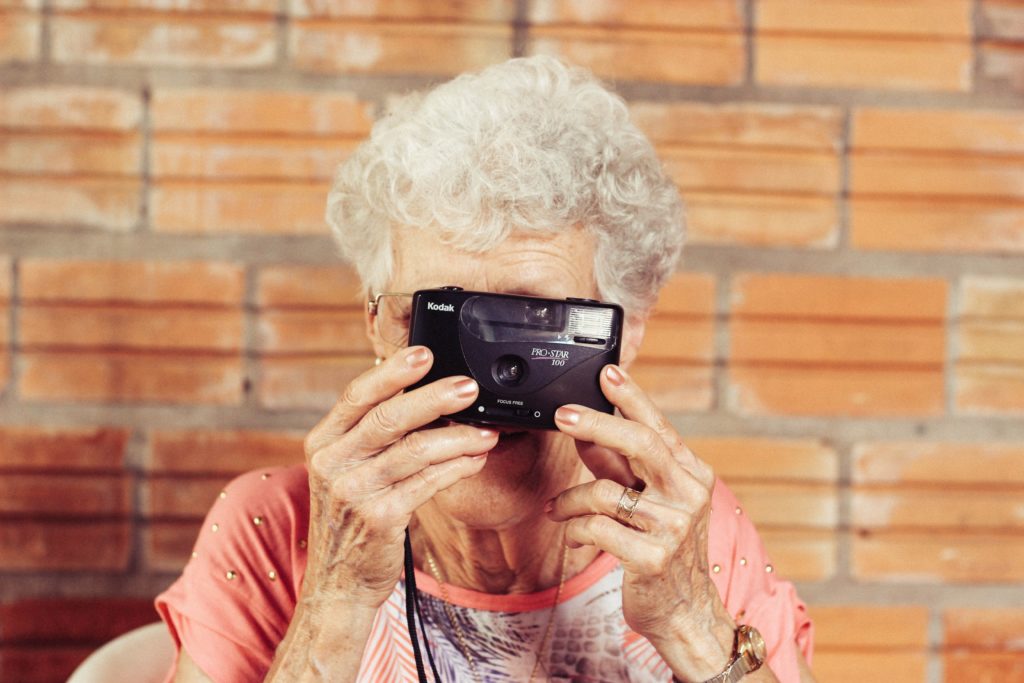 an older woman holding a camera over her face