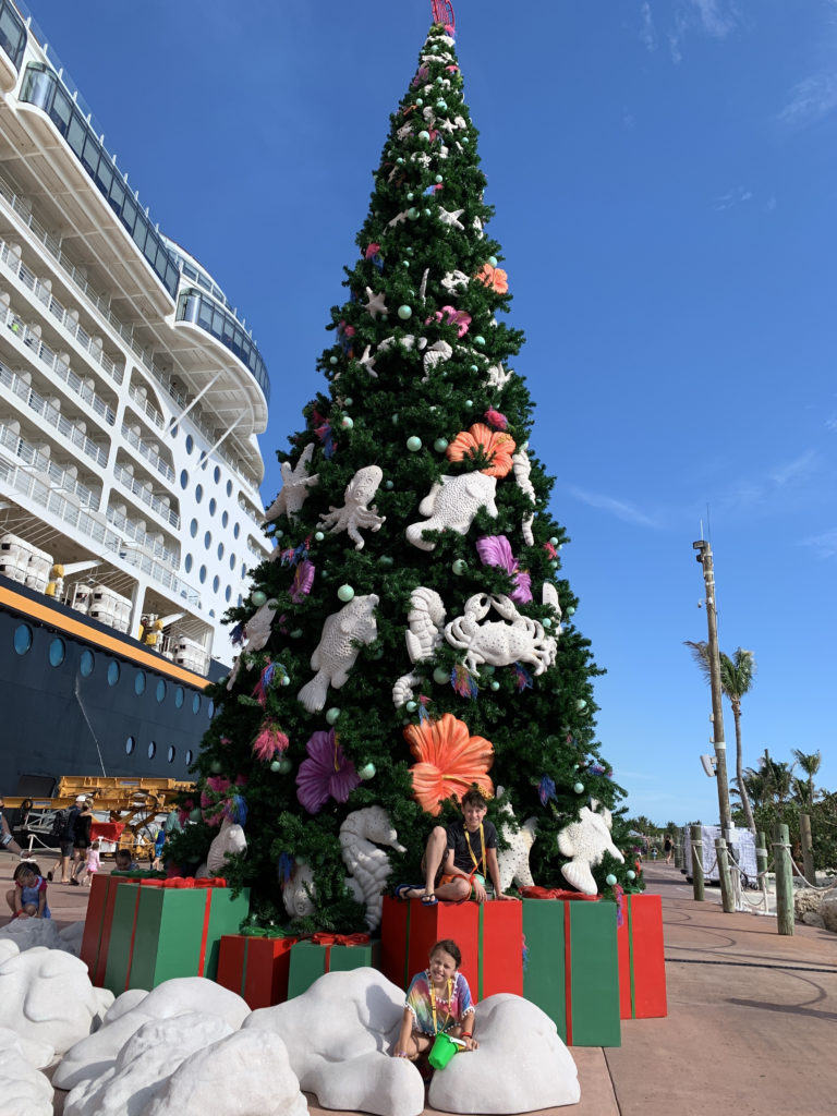 a christmas tree with a large tree and a cruise ship in the background