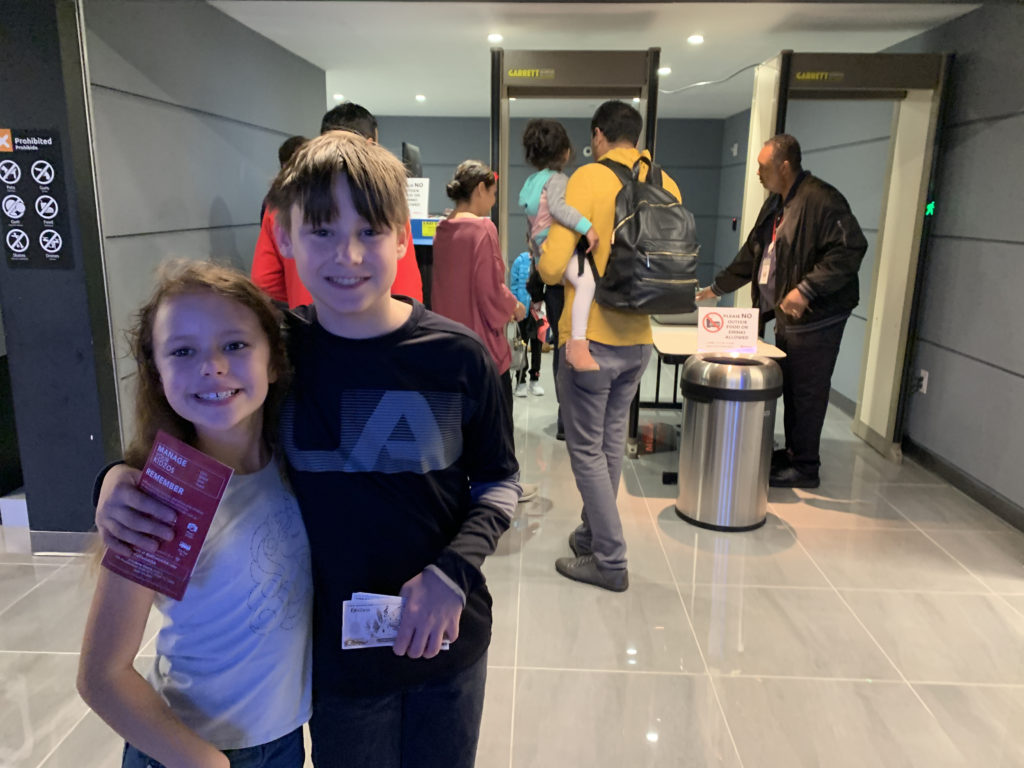 a boy and girl standing in a hallway with people in the background