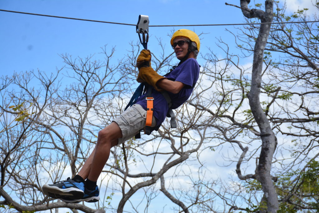 a man wearing a helmet and harness on a zip line
