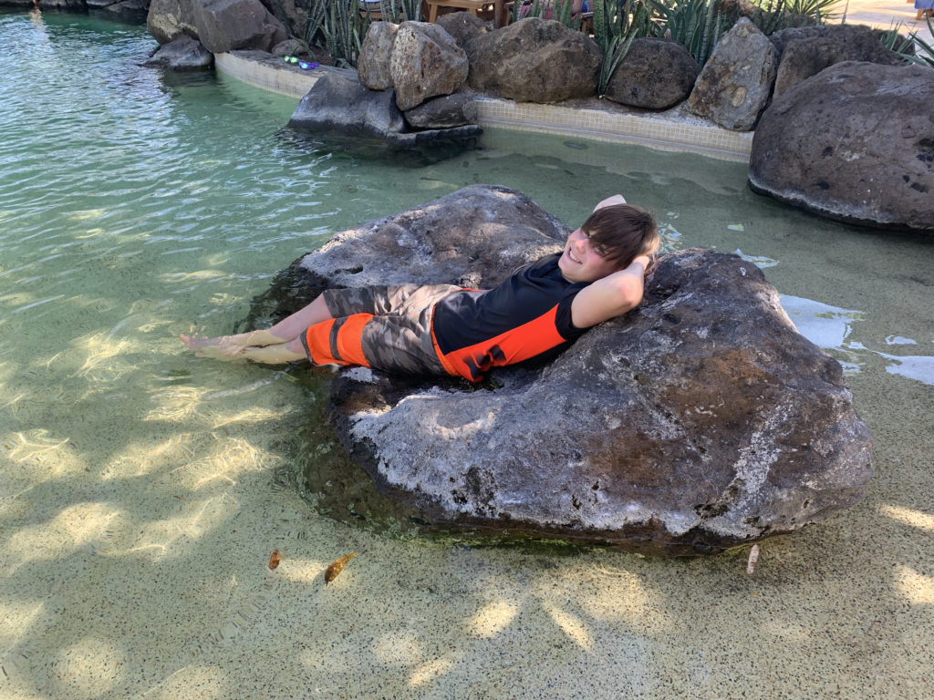 a boy lying on a rock in water