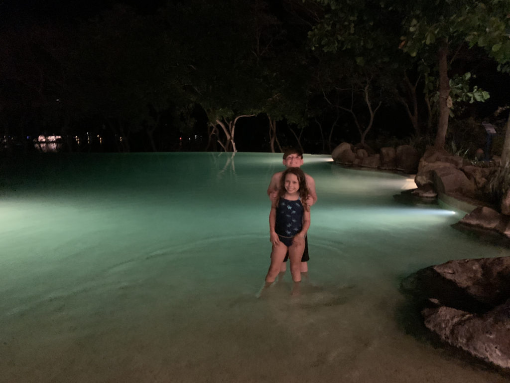 a man and woman standing in water at night