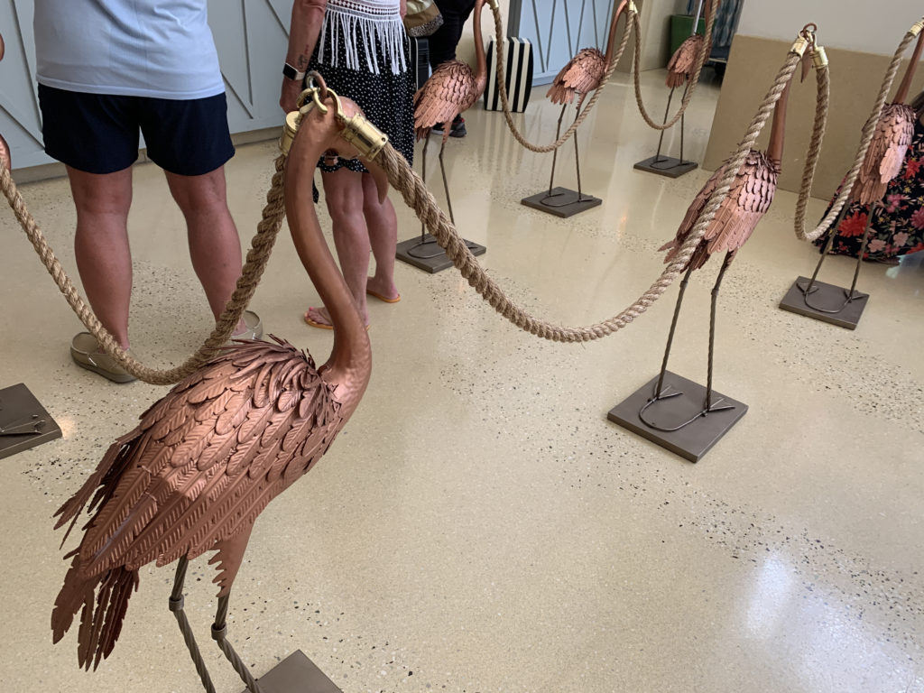 a group of people standing in a room with a group of statues of birds