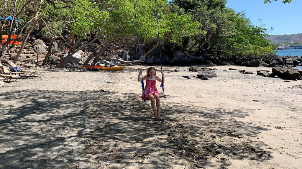 a girl on a swing on a beach