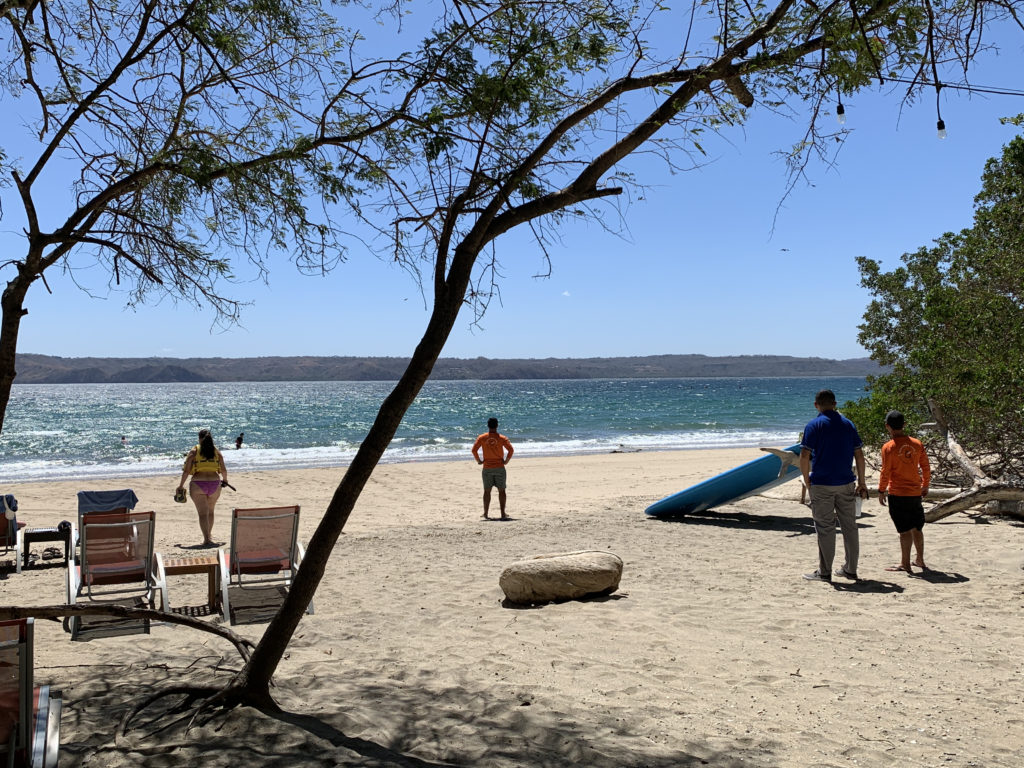 people on a beach with a surfboard and a body of water