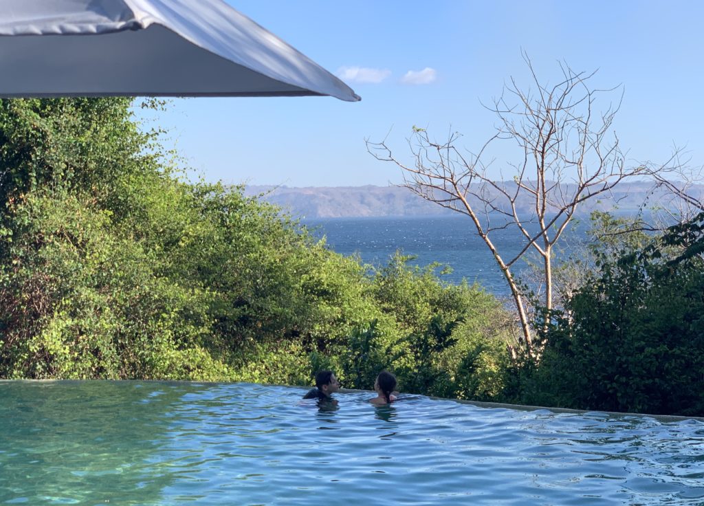 a couple in a pool with trees and water in the background