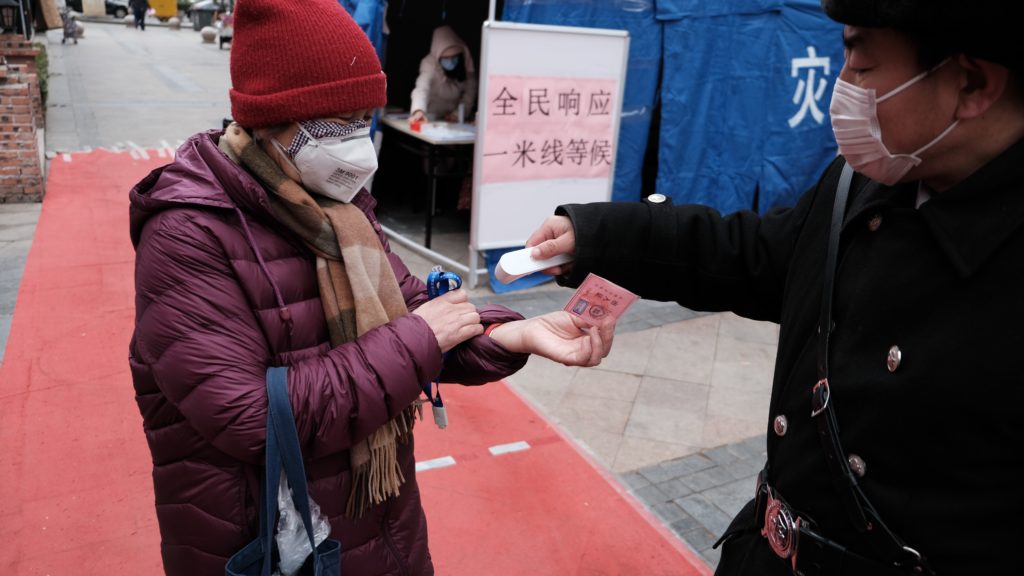 a person wearing a mask and a scarf receiving money from a person
