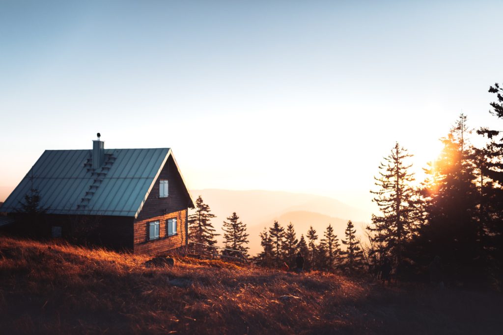 a house on a hill with trees and a sunset