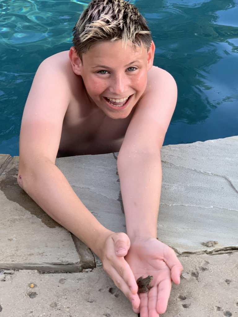 a boy holding a small fish in a pool