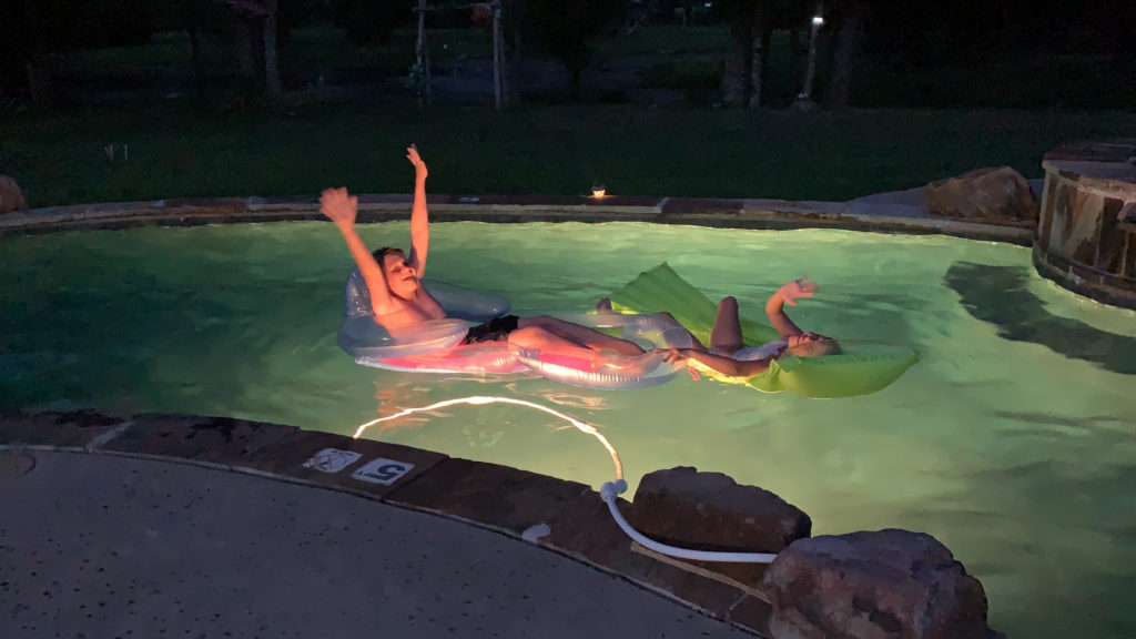 a couple of people floating on inner tubes in a pool at night