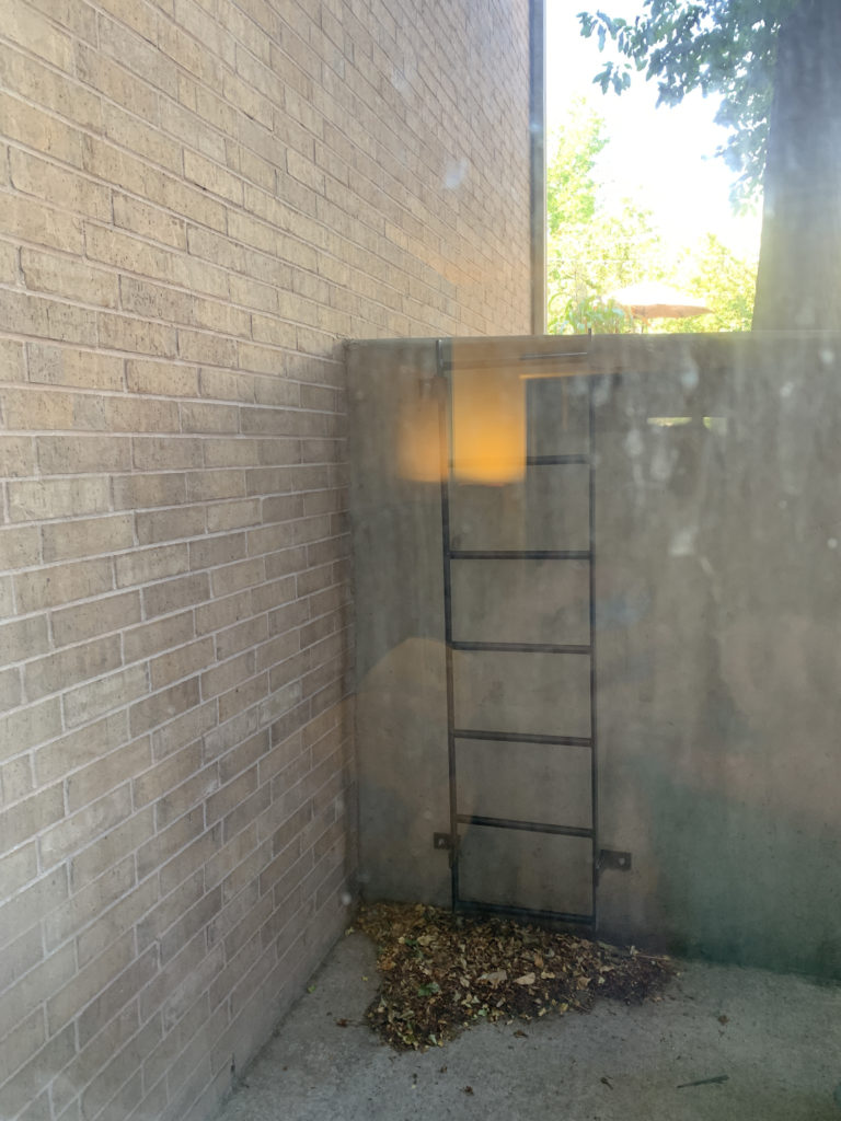 a ladder in a corner of a brick building