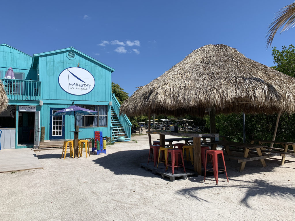 a blue building with a thatched roof and tables and chairs