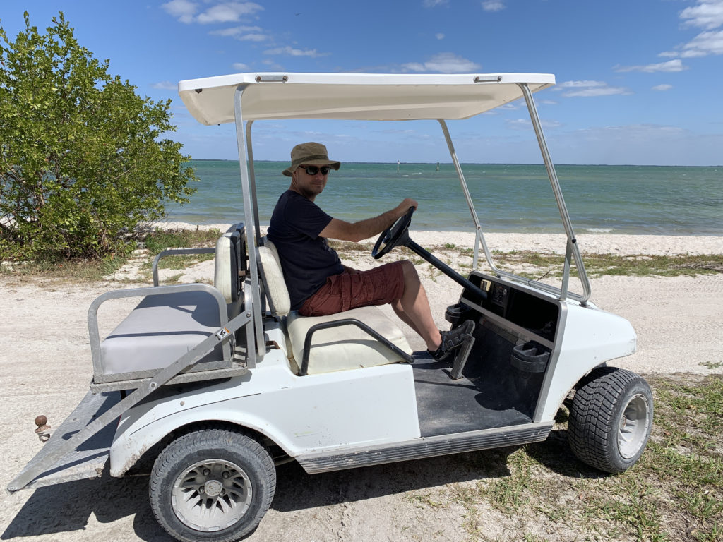 a man driving a golf cart on a beach