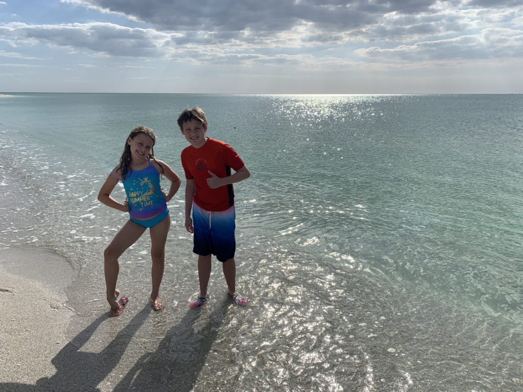 a boy and girl standing on a beach