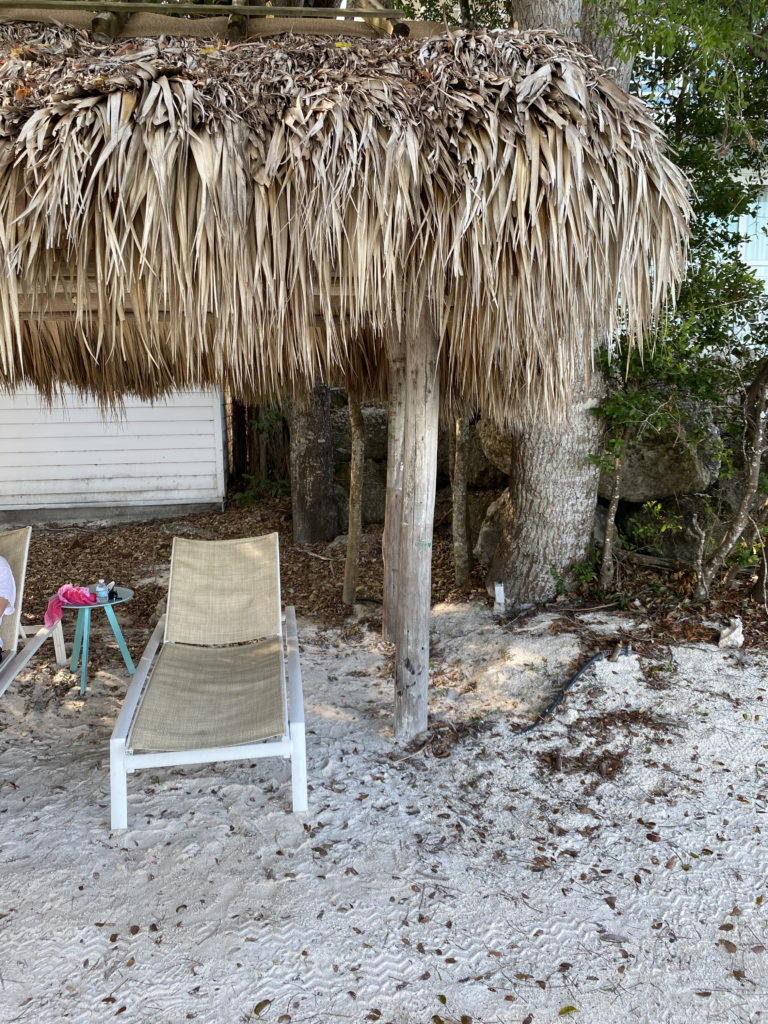 a person sitting on a chair under a straw umbrella