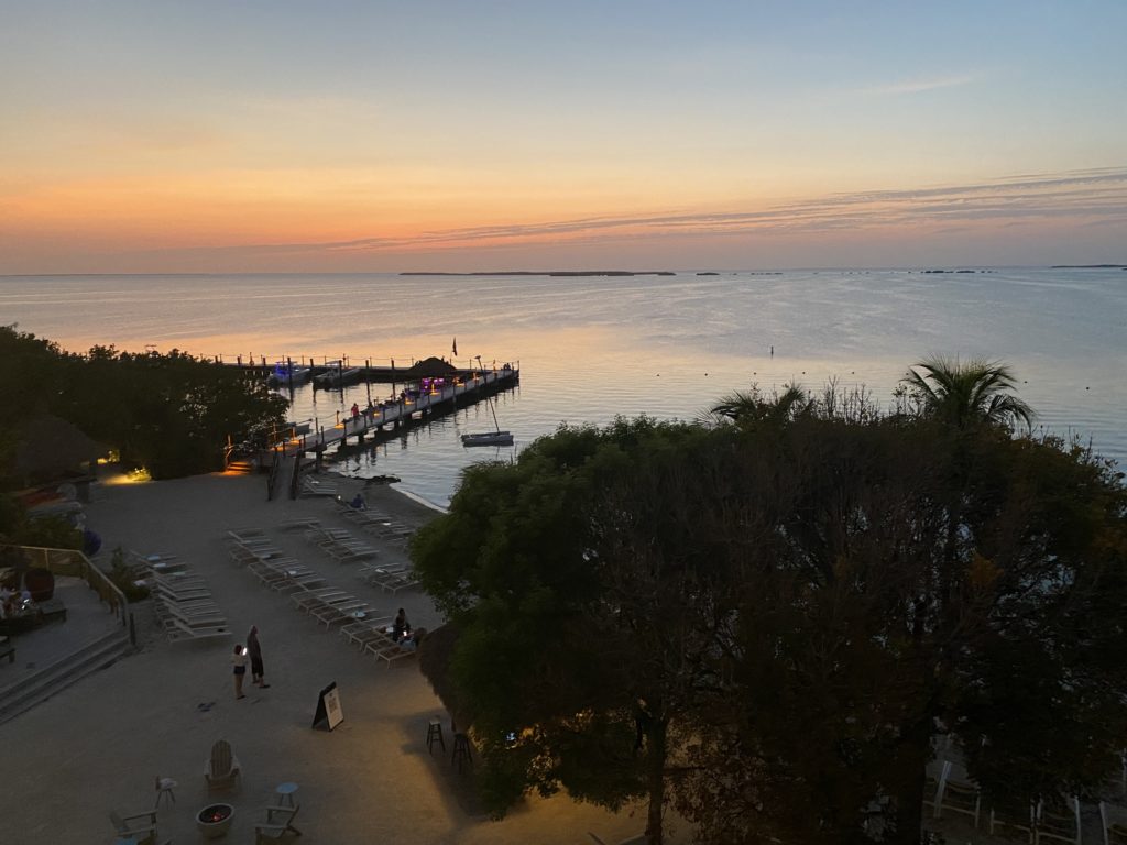 a beach with chairs and a dock in the water