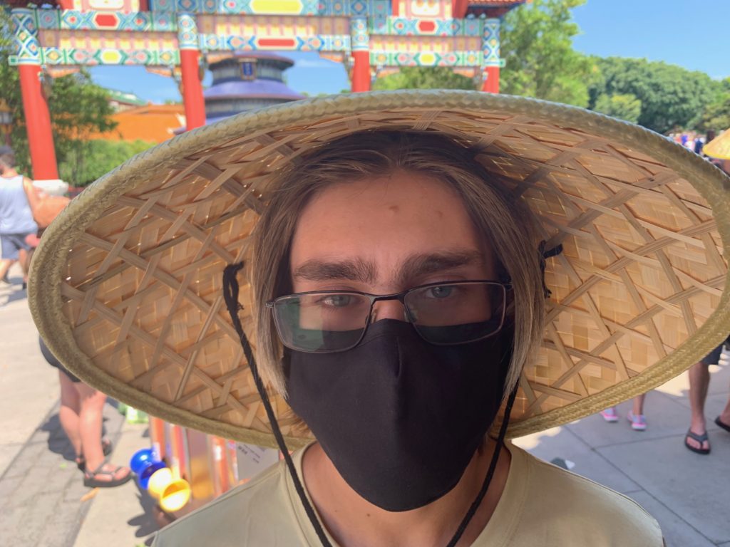 a man wearing a face mask and a straw hat