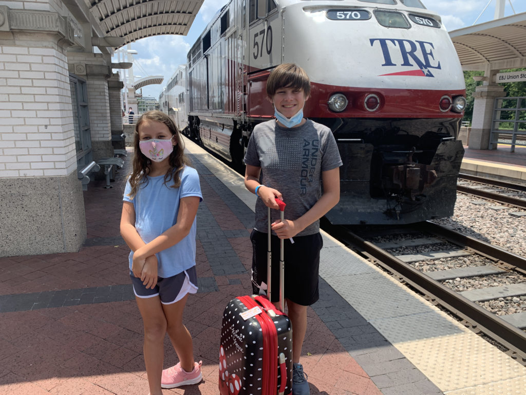 a boy and girl standing in front of a train