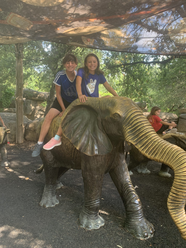 a boy and girl sitting on an elephant statue