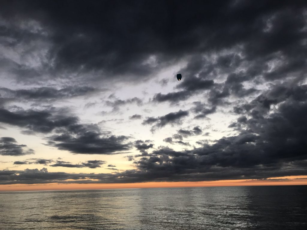 a body of water with a parachute in the sky