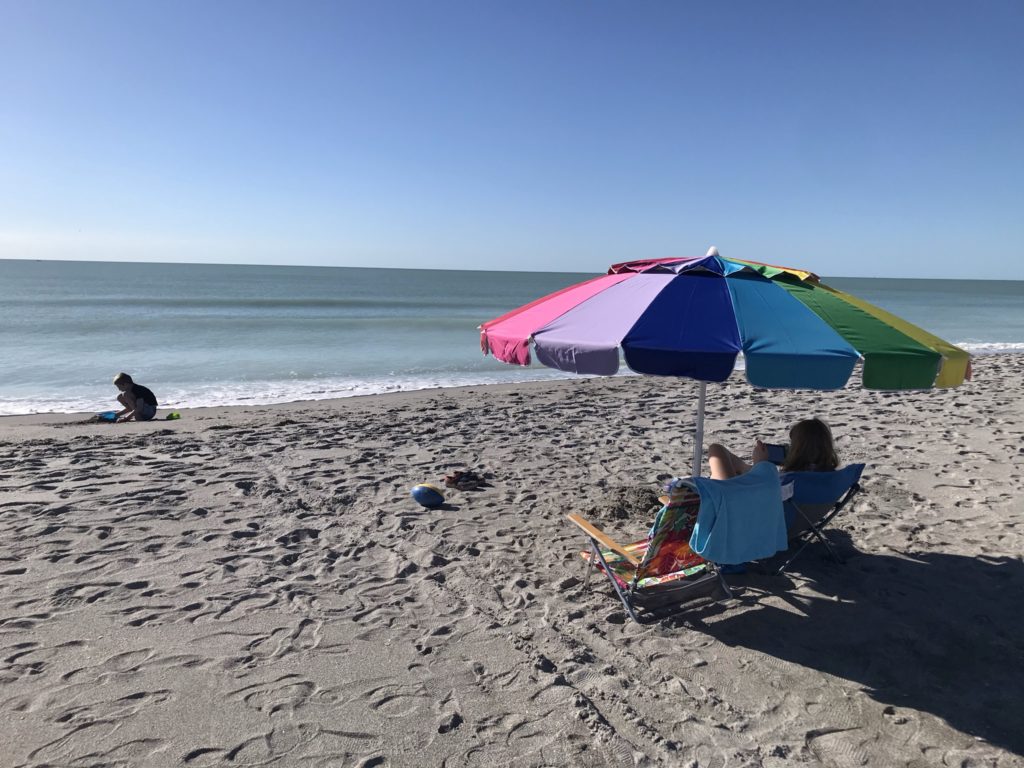 a person sitting under a colorful umbrella on a beach
