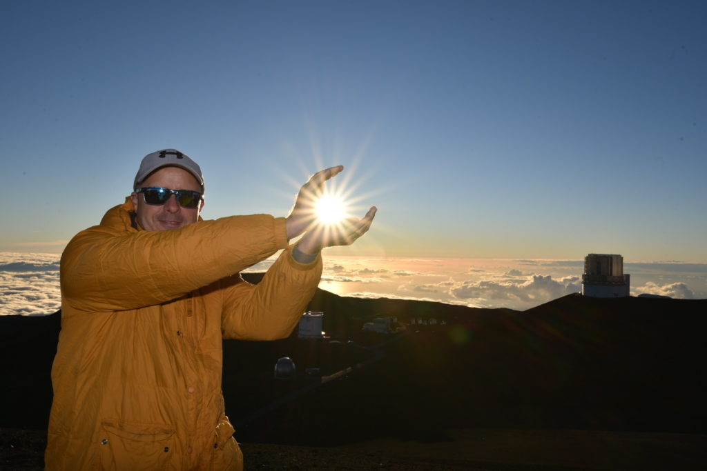 a man in a yellow jacket and cap with his arms out in the air