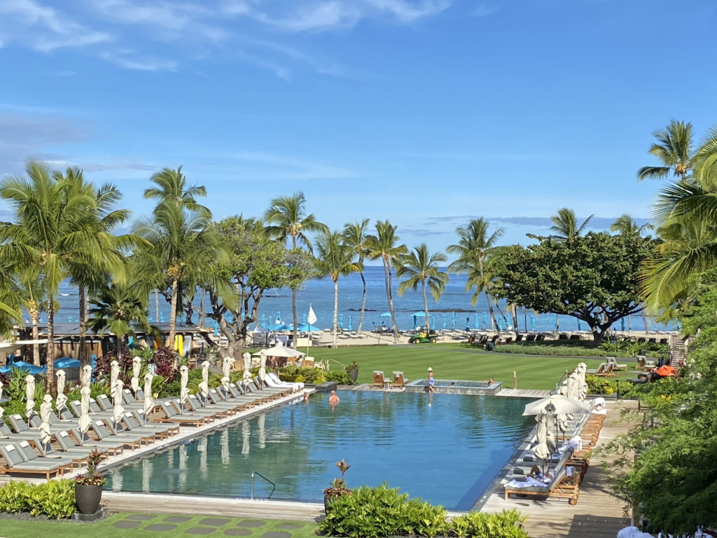 a pool with chairs and umbrellas in front of a beach
