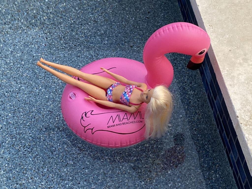 a doll in a swimsuit on a pink flamingo float