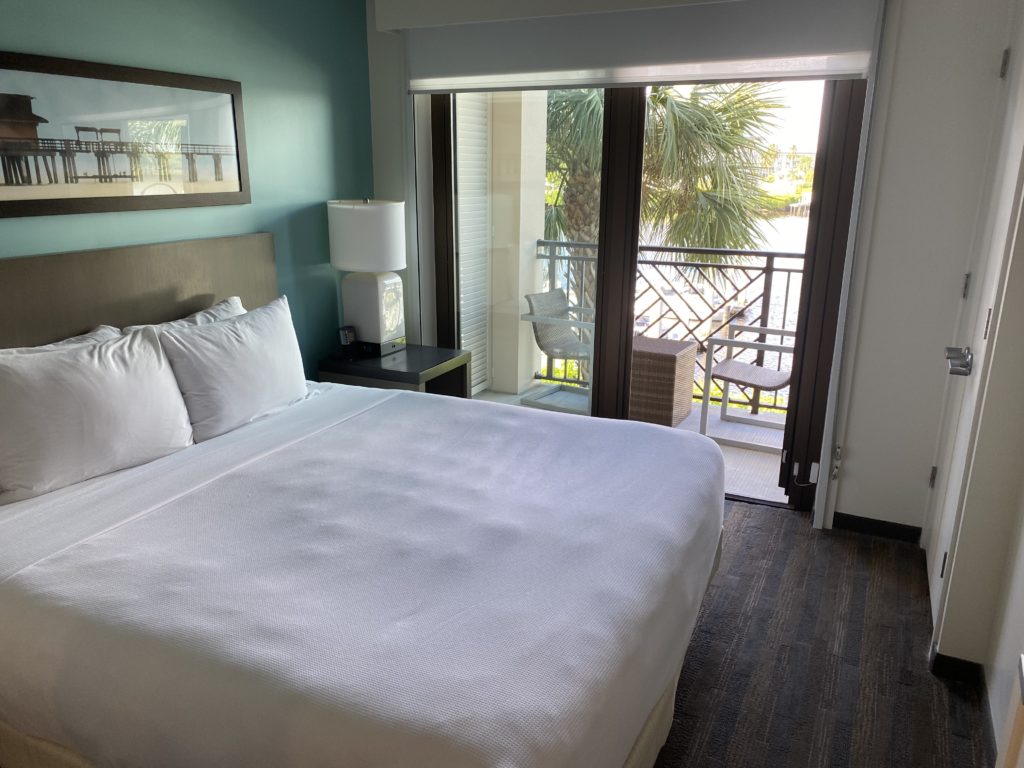 a bed with white sheets and a lamp next to a glass door