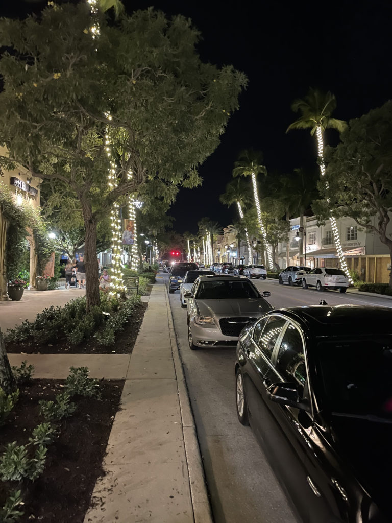 a street with cars and trees with lights on it