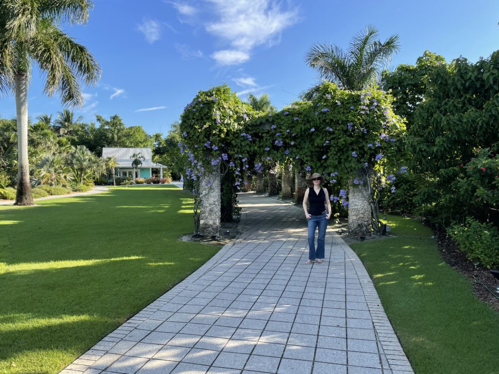 a woman standing on a brick path with trees and plants
