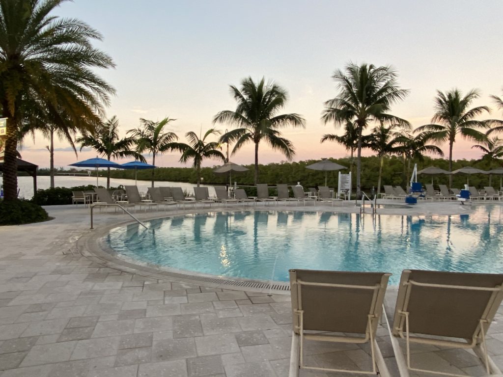 a pool with chairs and umbrellas by a body of water
