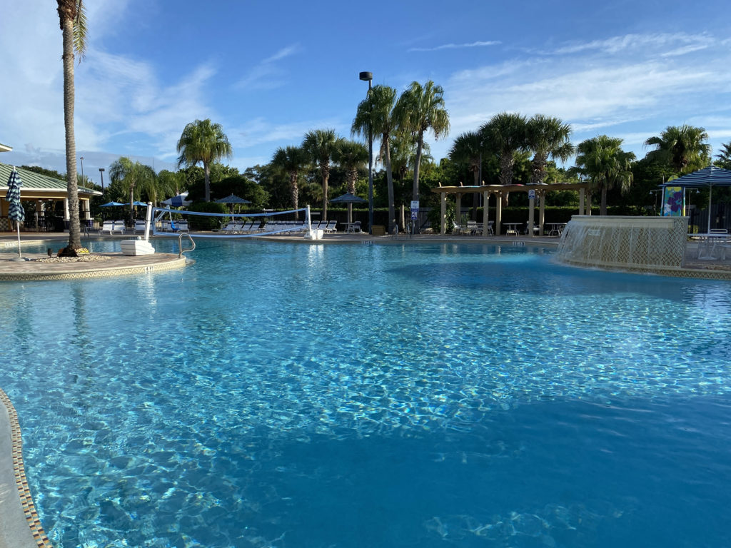 a pool with a volleyball net and palm trees