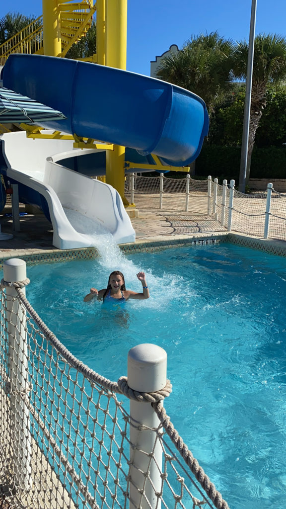a girl in a pool with a water slide